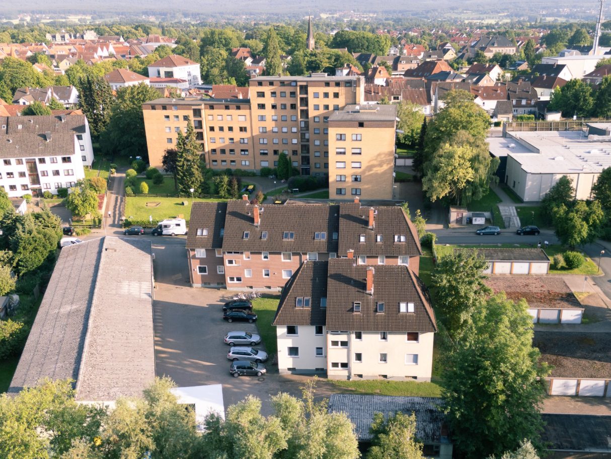 Luftaufnahme eines Wohngebiets mit mehreren Gebäuden und Grünflächen.
