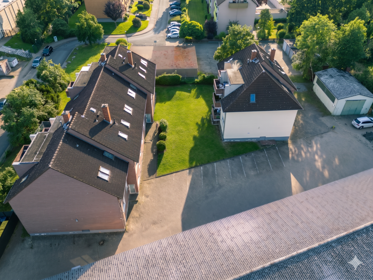 Luftaufnahme von Wohnhäusern mit grüner Rasenfläche und umliegenden Straßen.