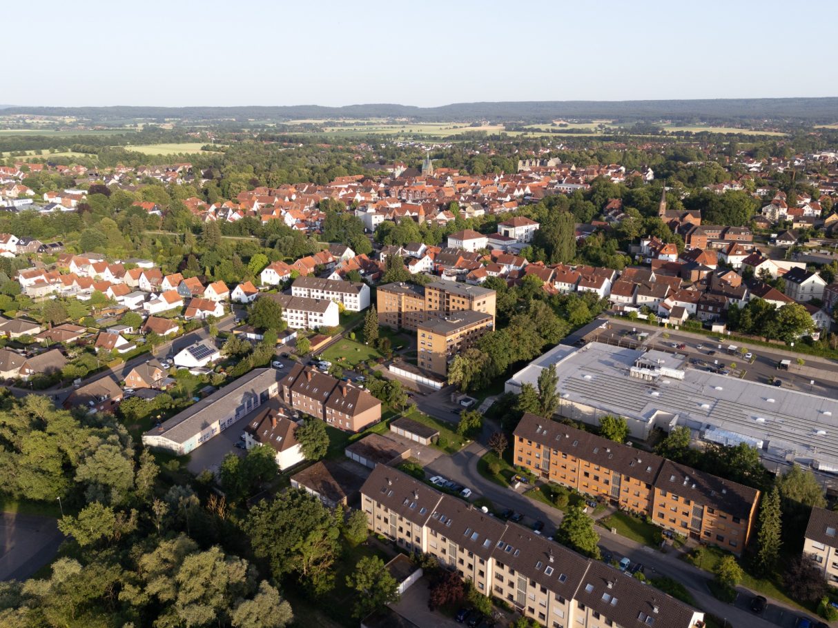Luftaufnahme einer Stadt mit Wohngebieten, Bäumen und einem historischen Gebäude.
