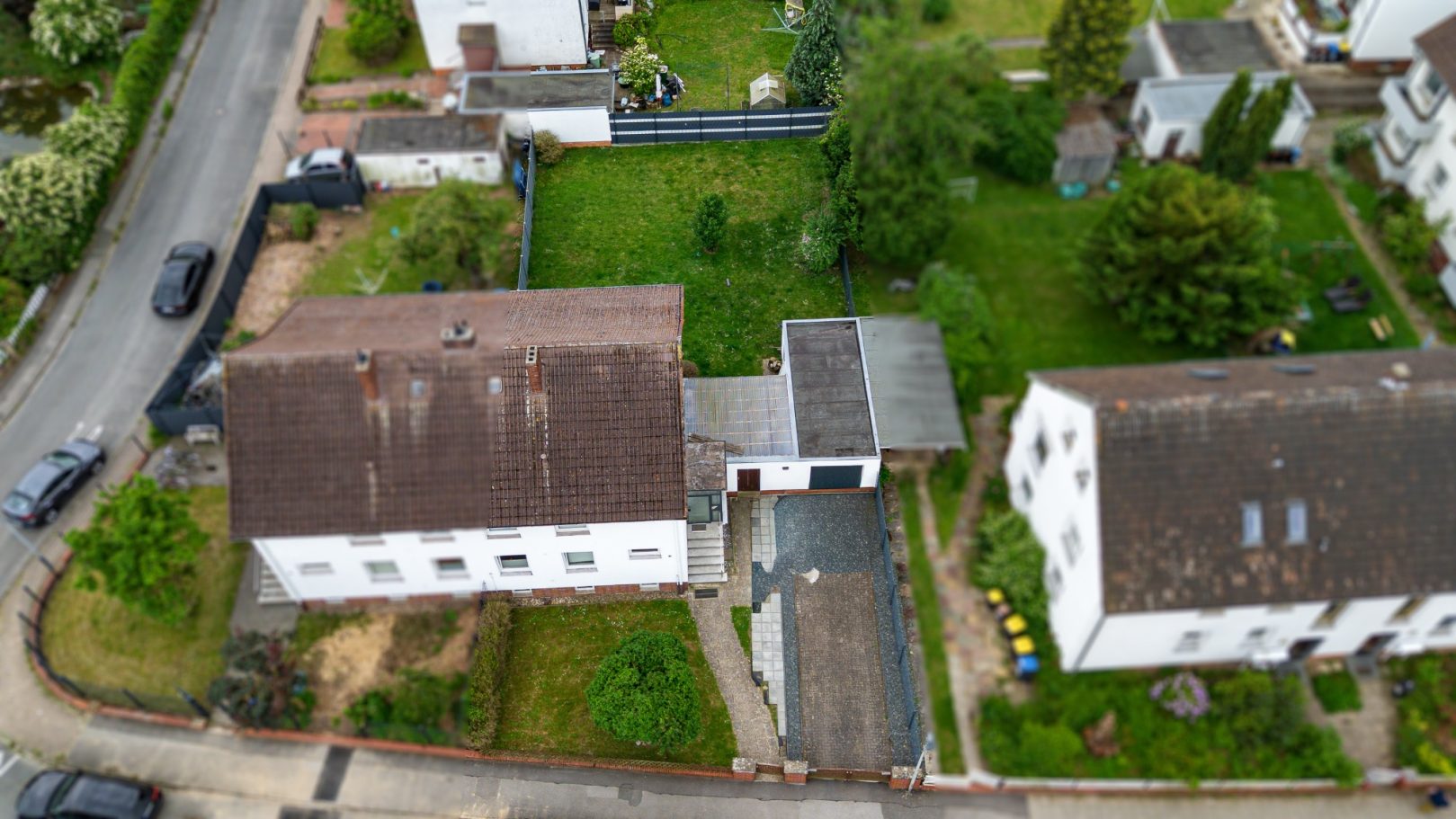 Luftaufnahme von zwei Wohnhäusern und einem Garten in einer ruhigen Wohngegend.